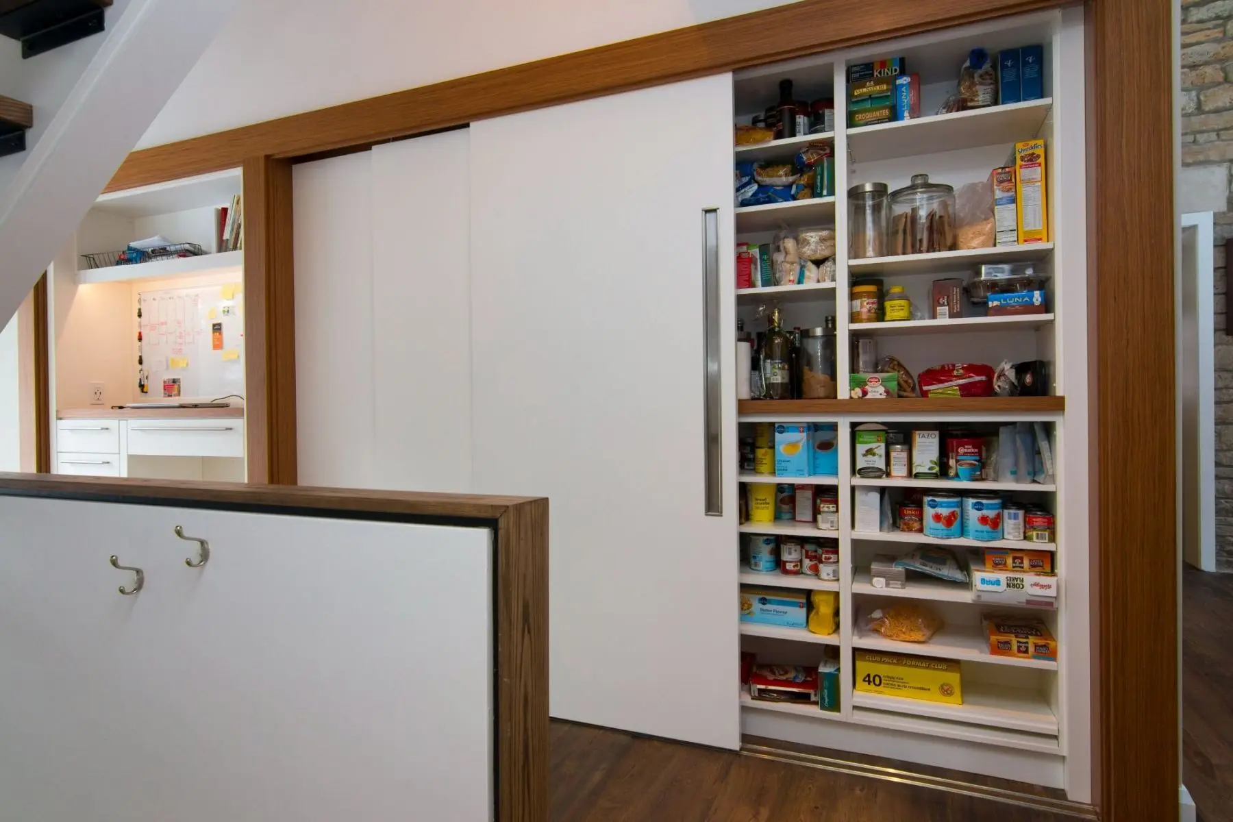 Custom pantry storage with sliding doors and organized shelves designed by Homestead Woodworks for an efficient and stylish kitchen space